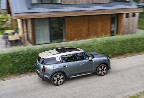 MINI Countryman driving past house.